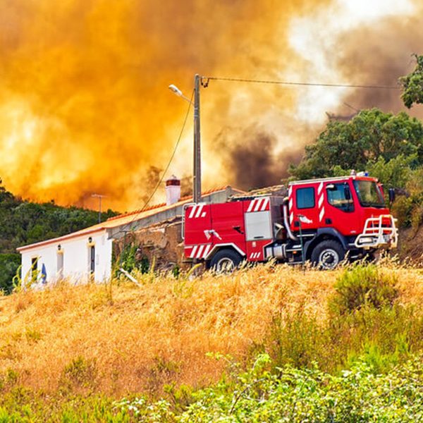 Wildfire burning in hills behind a building and commercial truck