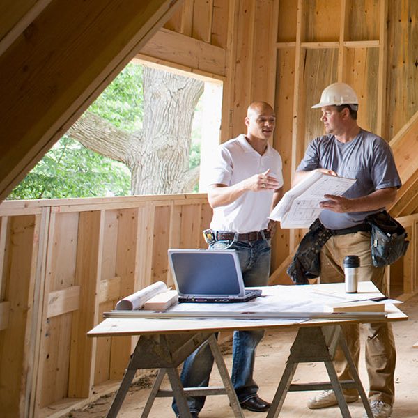 Two contractors talking in an unfinished attic