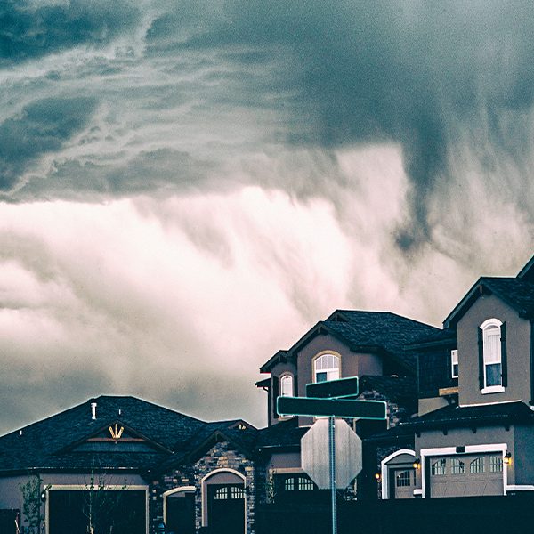 A street of houses with thick clouds building behind them